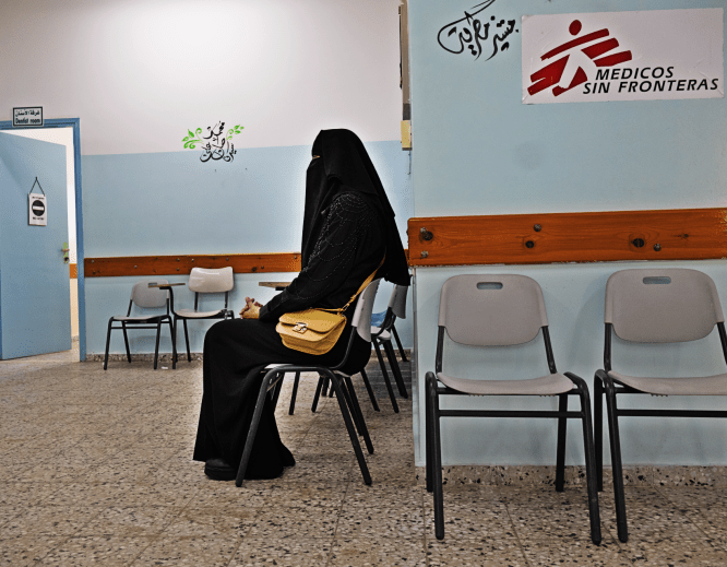 A veiled woman waits in a chair at an MSF facility in Gaza.