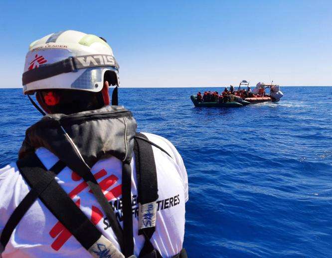 An MSF search and rescue staff member approaches a boat in distress in the Mediterranean.