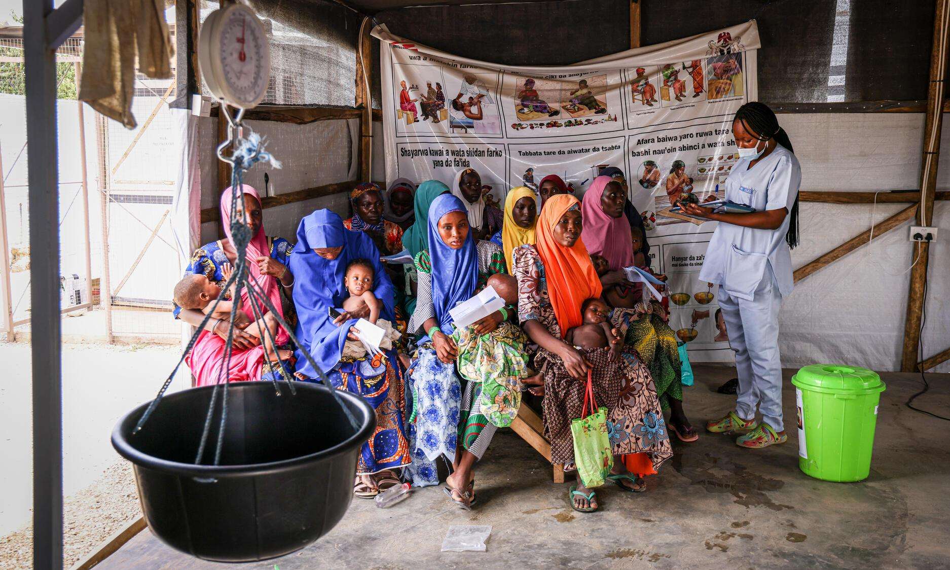 An MSF nurse meets with a group of women and children in a tent in Nigeria.