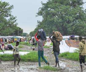 Men carrying their belongings on their heads arrive in South Sudan after fleeing violence in Sudan.